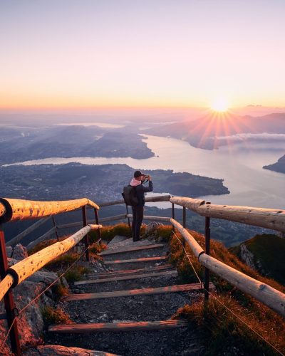 Man photographing landscape at beautiful sunrise pessoa em uma escada tirando foto de uma vista incrível
